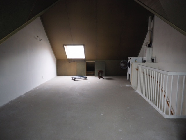 Voor de installatie van een dakkapel, donkere zolder met klein raam.