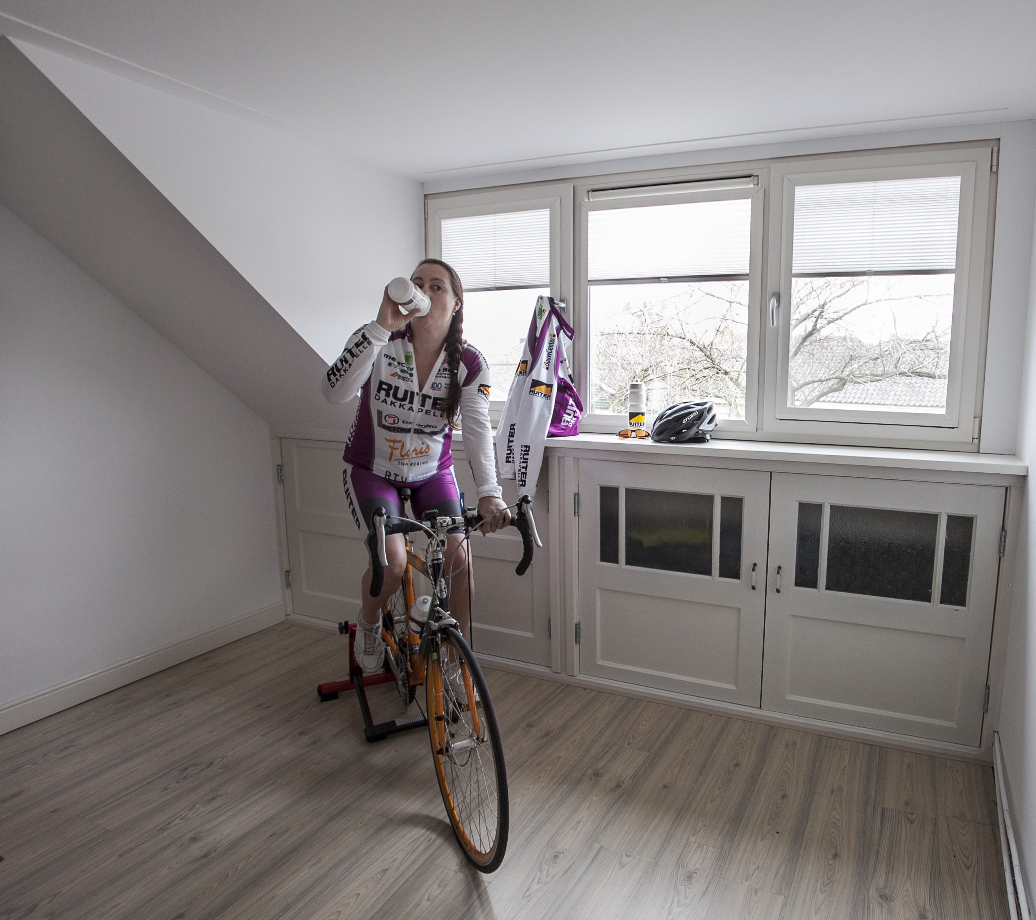 Extra ruimte dakkapel voor een fitness zolder. Vrouw op fitness fiets.