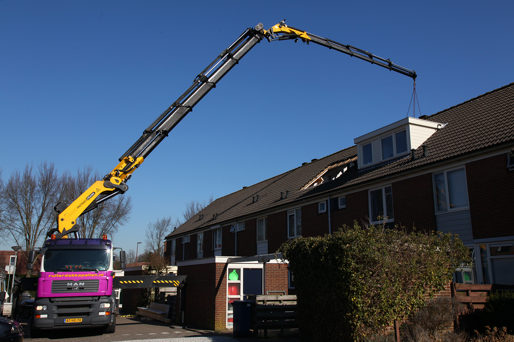 Kraan plaatst een prefab dakkapel.